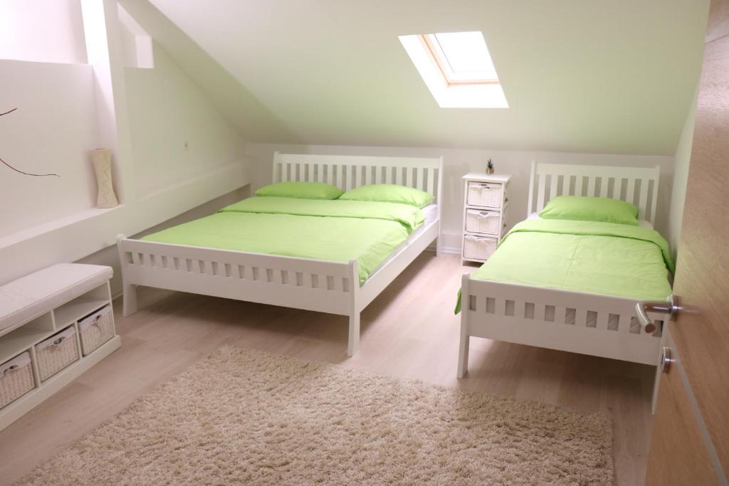 特拉夫尼克Apartment Vremeplov的白色客房的两张床,配有绿色床单