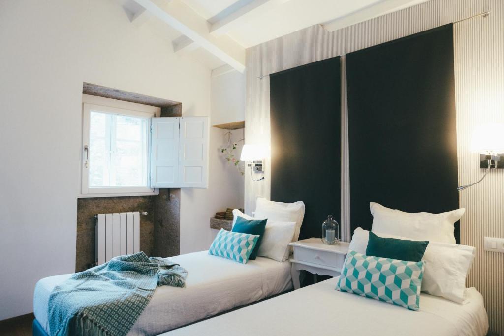 圣地亚哥－德孔波斯特拉奥里利亚蒂卡公寓的一间卧室配有两张带蓝白色枕头的床