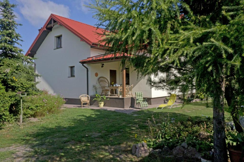 Biały ŁugAgroturystyka pod Czarną Sosną的白色的房子,有红色的屋顶和院子