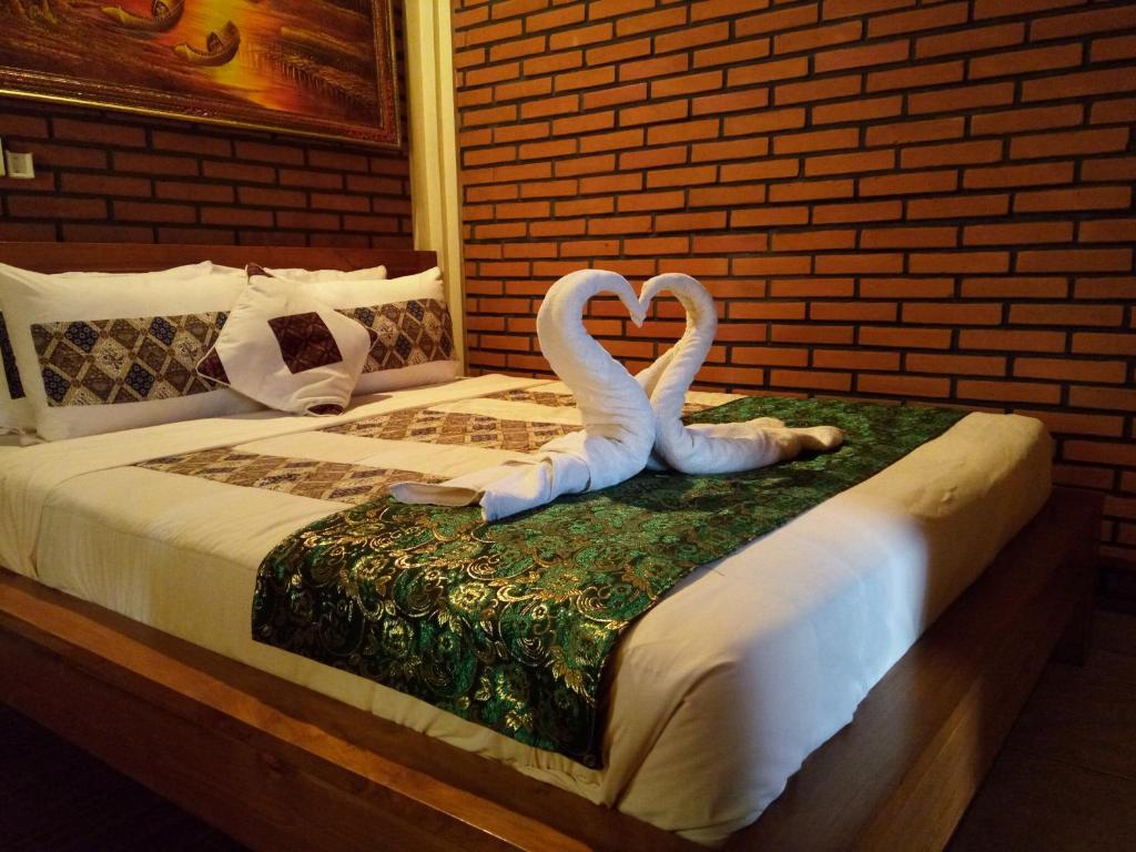 乌布独特寄宿酒店的两个天鹅 ⁇ 地躺在床上,看起来像个心