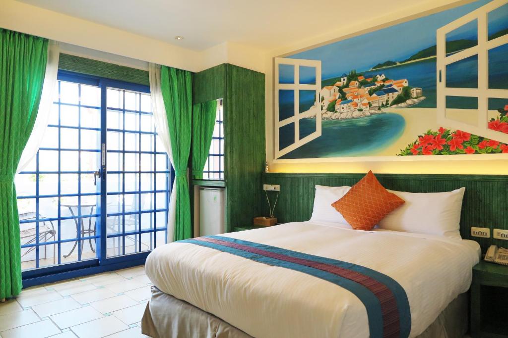 垦丁大街垦丁欣欣渡假旅馆二馆的卧室配有一张大床,墙上挂有绘画作品