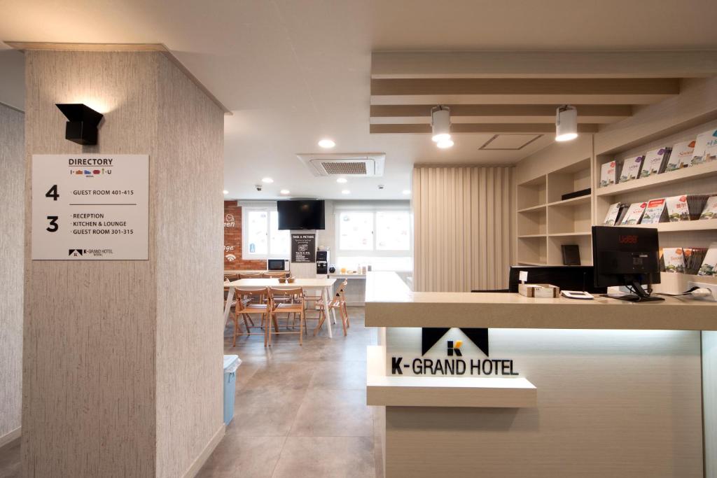 首尔K-Grand Hotel Seoul的客房设有一个柜台和一张桌子及椅子