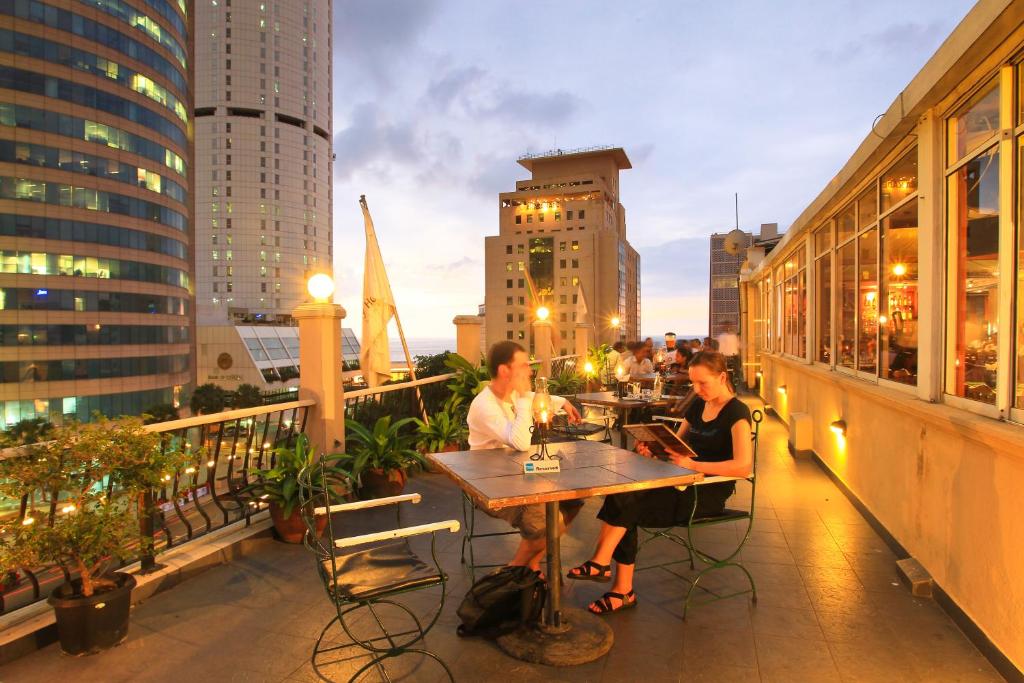科伦坡Colombo City Hotels (Pvt) Ltd的坐在阳台上桌子上的男人和女人