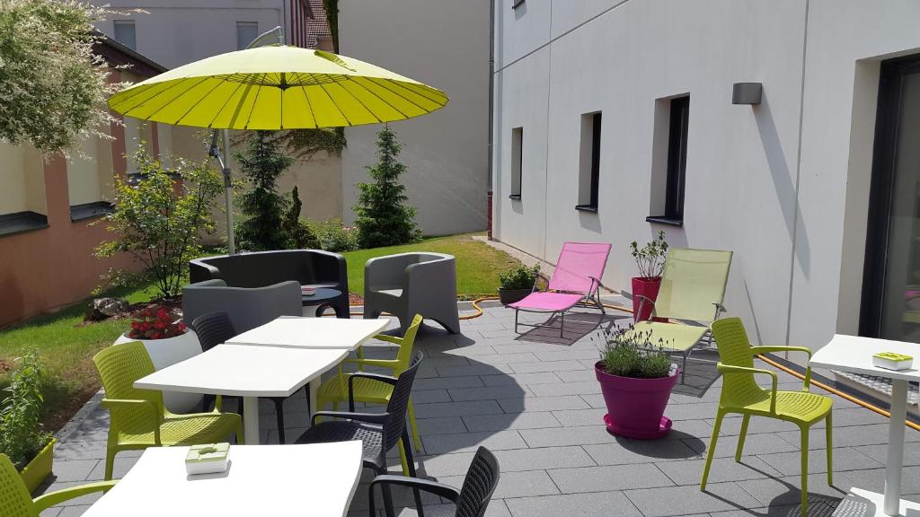蒙贝利亚尔蒙贝利亚尔宜必思尚品酒店的庭院配有桌椅和黄色雨伞。
