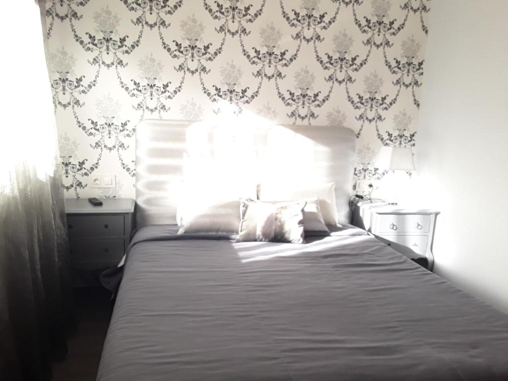 坎德拉里奥Hostal Restaurante Pasaje的一间卧室配有一张带白色床单和壁纸的大床。