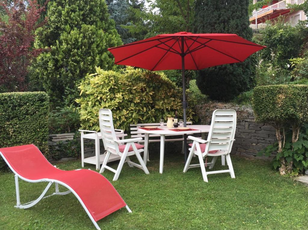 奥斯塔Maison Bibian的一张桌子和椅子,配有红色雨伞