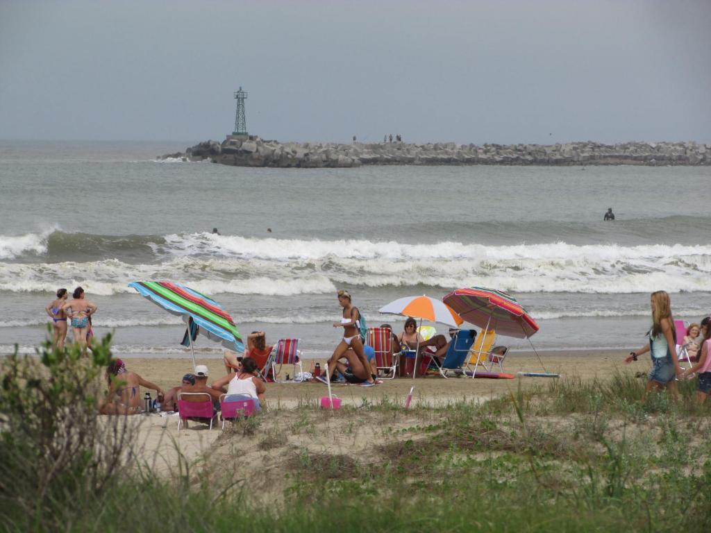 拉帕洛马La Nueva Ensenada的一群人坐在海滩上,拿着遮阳伞