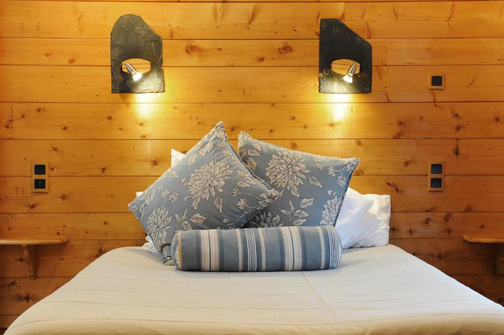 ViscosHôtel La Grange Aux Marmottes的木墙上一张带两个灯的床