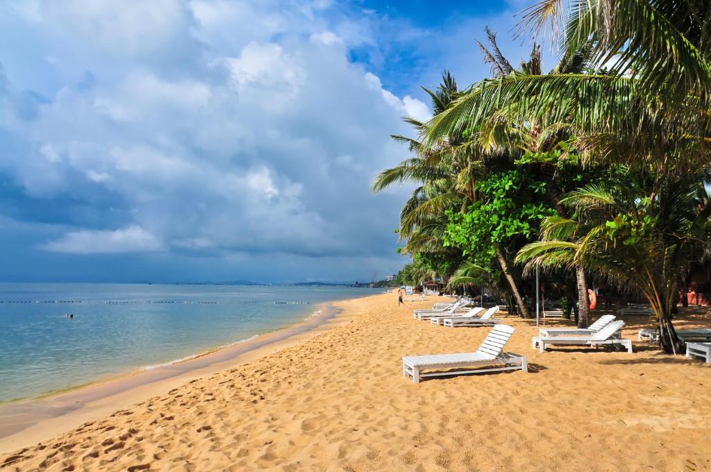 富国海之星度假酒店的海滩上设有躺椅和棕榈树,还有大海