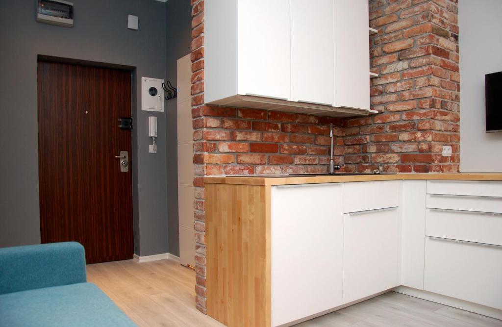 华沙Studio Nowy Świat的厨房配有白色橱柜和砖墙