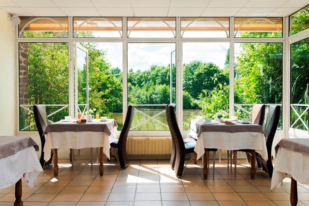 瑟松塞维涅乐生发酒店的一间带两张桌子和大窗户的用餐室
