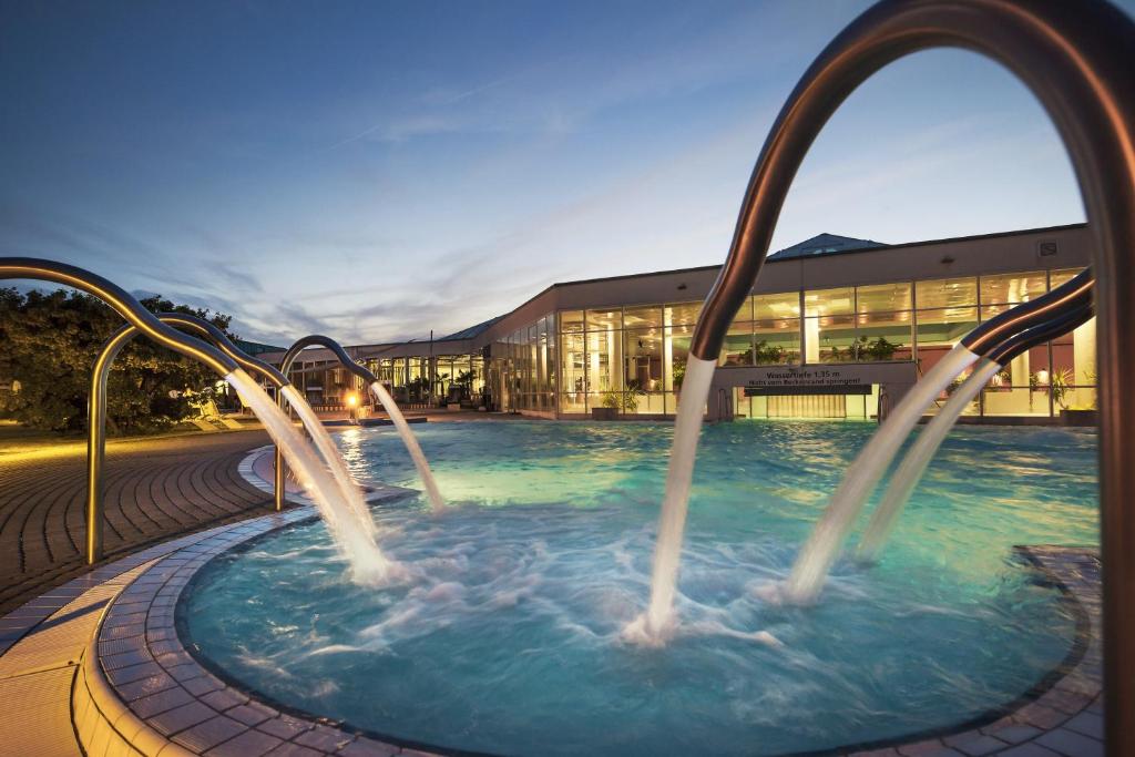 巴特迪本海德Spa度假酒店的一座大楼前带两个水滑梯的游泳池