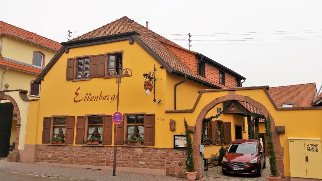 Heßheim艾伦伯格餐厅及酒店 的一座黄色的建筑,前面有一辆汽车