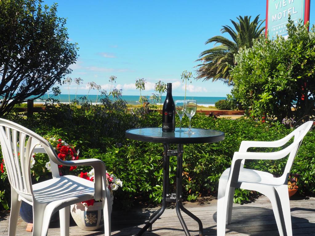 奥霍普海滩Ocean View的一张桌子、一瓶葡萄酒和两把椅子
