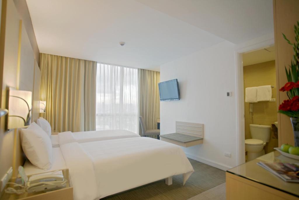 马尼拉St Giles Hotel Makati的酒店客房设有白色的床和电视。