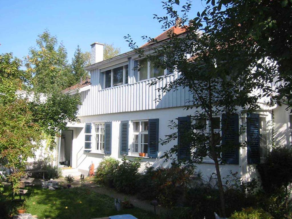 康斯坦茨Ferienwohnung CHRIS的白色的房子,有黑色百叶窗和院子
