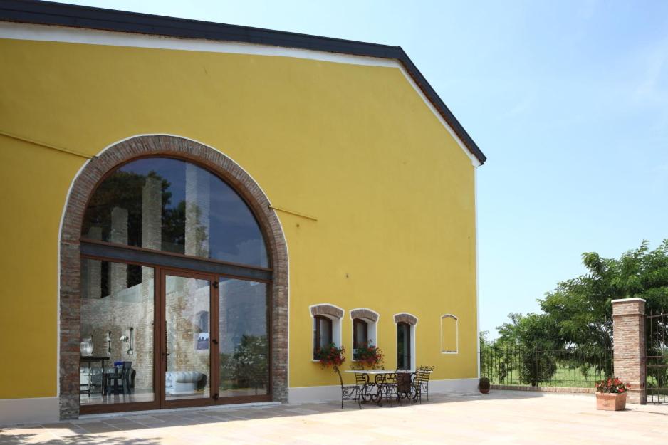 Curtatone科尔特卡皮路皮亚农家乐的黄色的建筑,设有大窗户和桌子