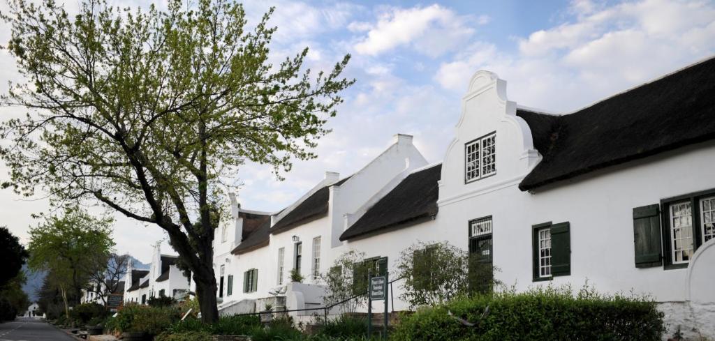 塔尔巴赫Tulbagh Country Guest House - Cape Dutch Quarters的白色的房子,有黑窗和树