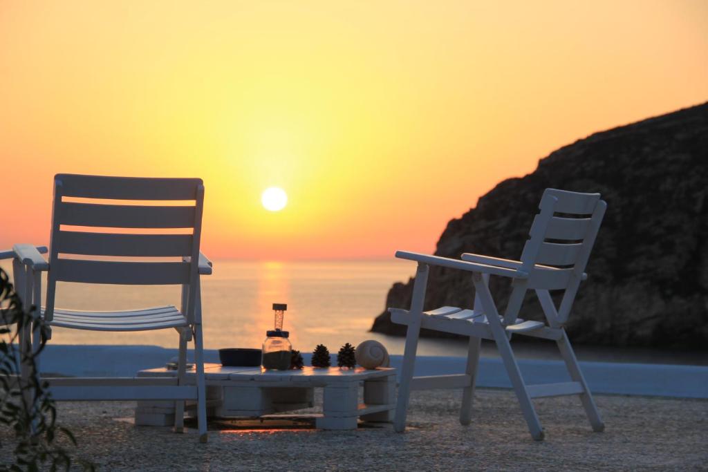 阿波罗弗洛拉公寓的海滩上的两把椅子和一张桌子,享有日落美景