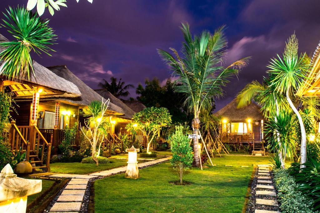 蓝梦岛Koji Garden Huts - CHSE Certified的棕榈树和灯火的夜间度假村