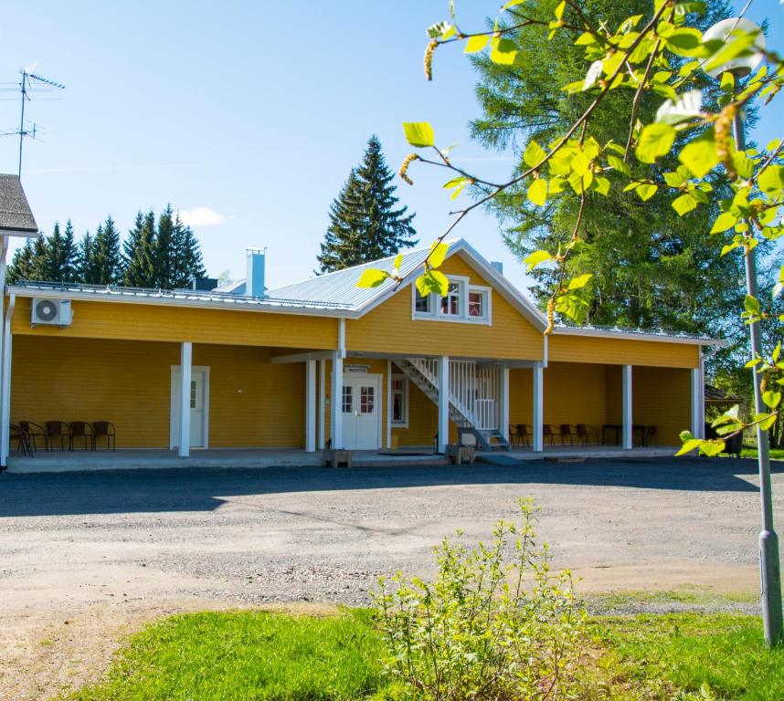 UtajärviMerilän Kartano的黄色房子,有门廊和树木