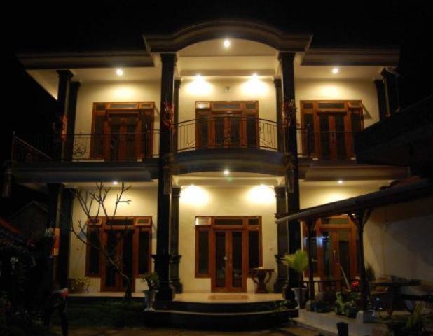 姆杜克阿迪亚芒杜克民宿的一座白色的大建筑,晚上设有阳台