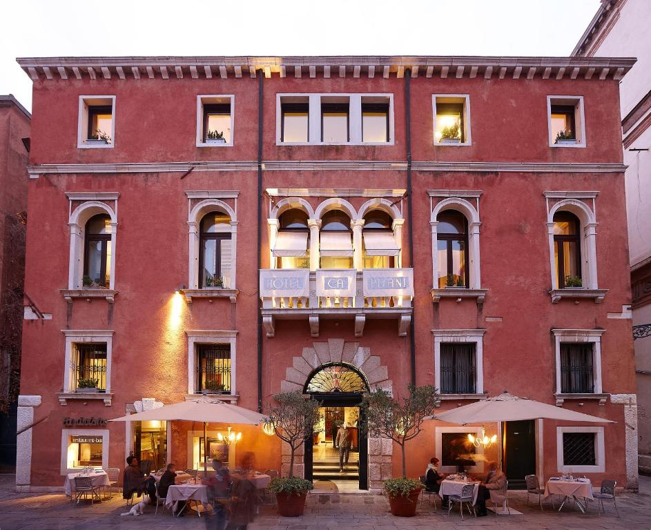 威尼斯卡皮萨尼酒店的一座红色的大建筑,外面的人坐在