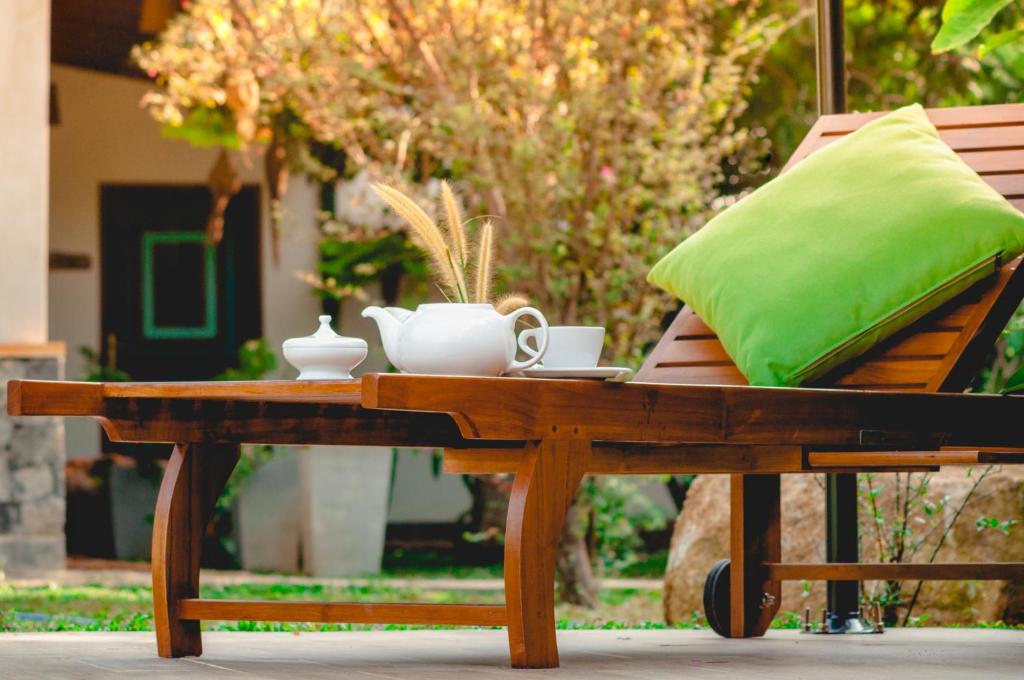 希克杜沃叶藤黄酒店的一张带绿枕头和杯子的木桌