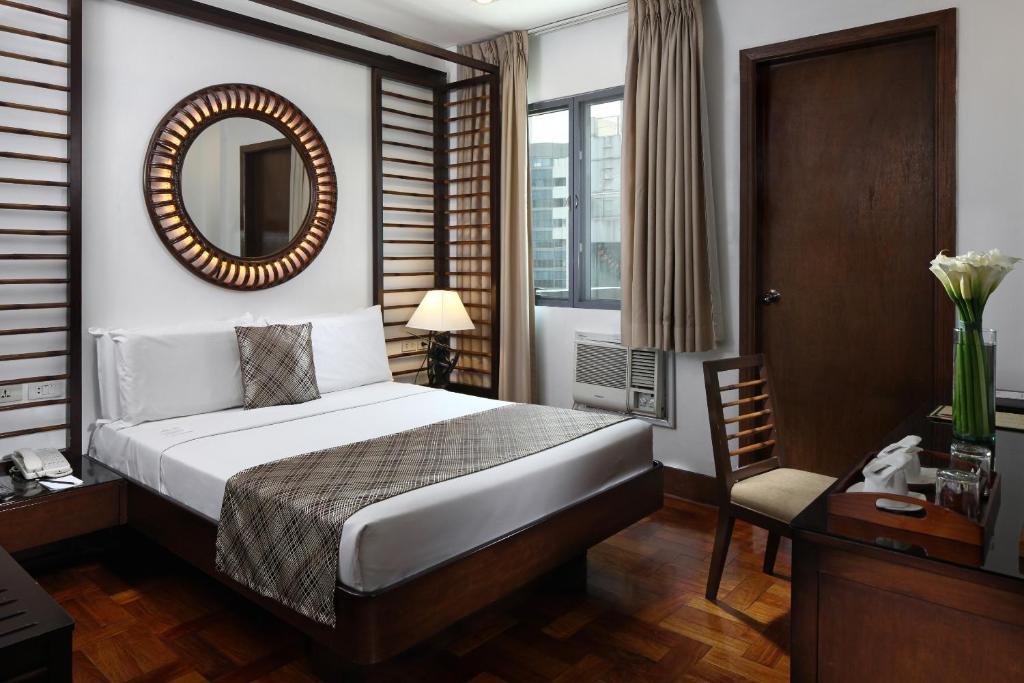 马尼拉Manila Lotus Hotel的一间卧室配有一张床、镜子和椅子