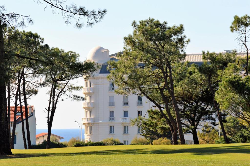 比亚里茨Apartment Golf Beach Régina Biarritz的前方有树木的白色建筑
