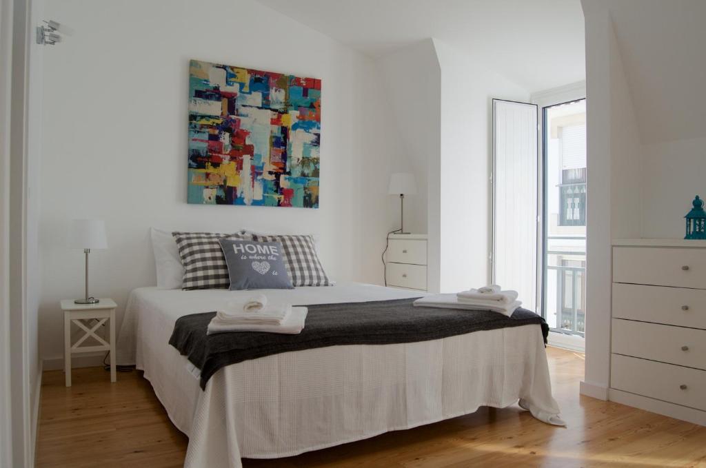 卡斯卡伊斯Casa do Chafariz的白色卧室配有一张床,墙上挂着一幅画
