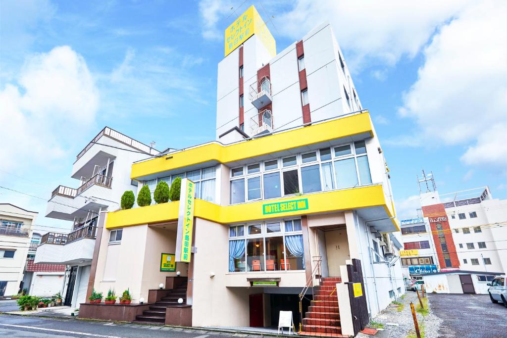 岛田岛田站前精选旅馆的城市街道上的一座黄色和白色的建筑