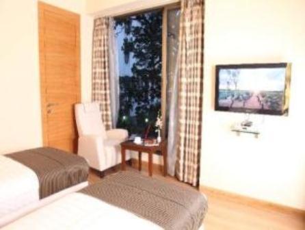 加尔各答米德尔顿旅馆的一间卧室配有一张床和一个带椅子的窗户