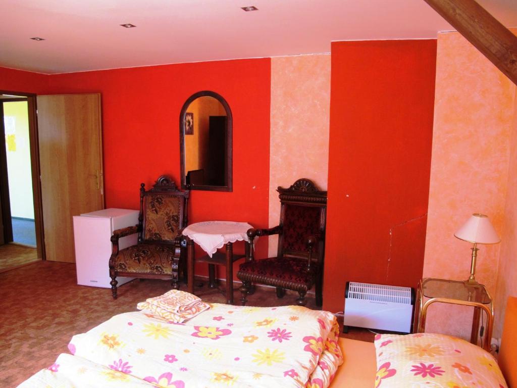HošťkaHotel U Lišky的一间卧室设有红色的墙壁、一张床和镜子