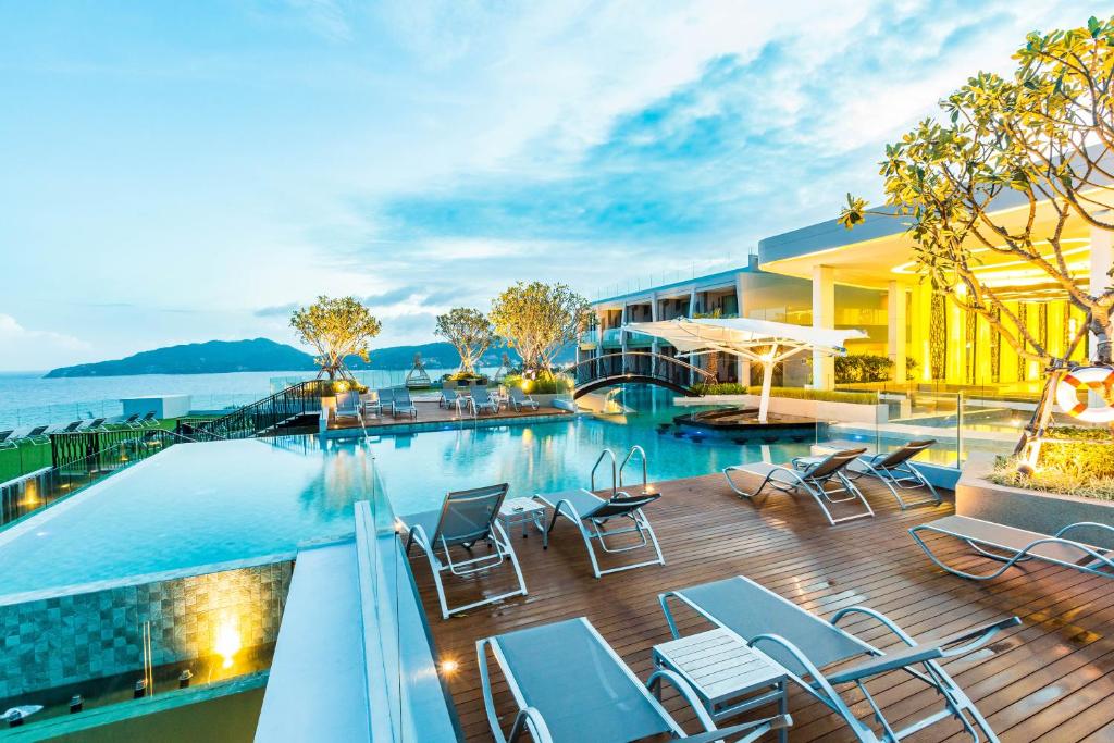 芭东海滩Crest Resort & Pool Villas - SHA Extra Plus的一座酒店,在甲板上设有游泳池和椅子