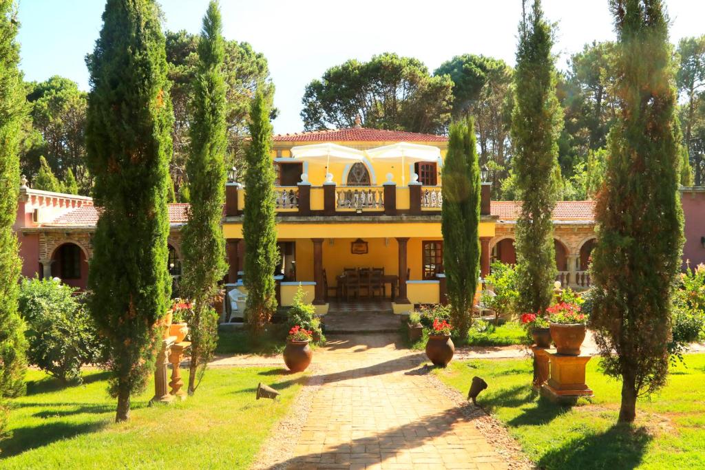 埃斯特角城Villa Toscana Boutique Hotel -Adults Only的带阳台和树木的大型黄色房屋