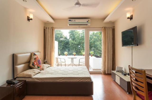 新德里纪念碑宁静公寓的一间卧室配有一张床、一张桌子和一台电视