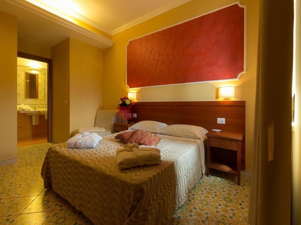 庞贝庞贝佛图纳村旅馆的酒店客房,配有床和一张桌子,上面有毛巾
