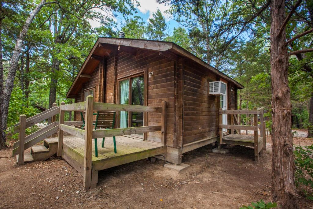 Willow Spring特克索马湖露营地度假村小屋4号假日公园的树林中的小木屋,设有门廊