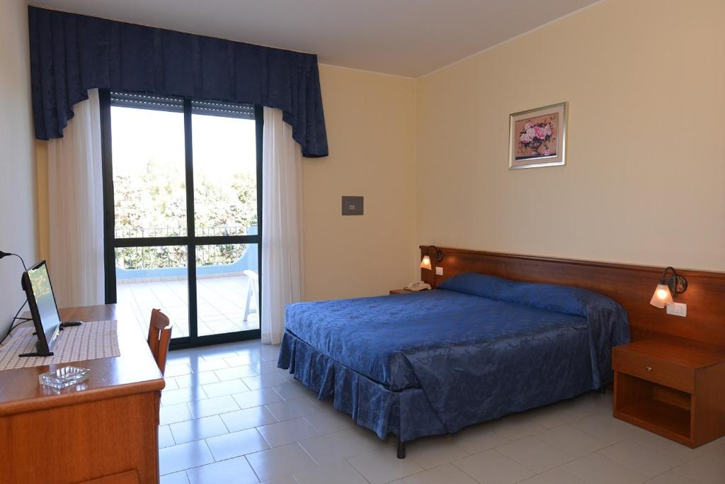 贝瓦尼亚圣彼得Hotel Villaggio Aurora的一间卧室配有一张床、一张书桌和一个窗户。