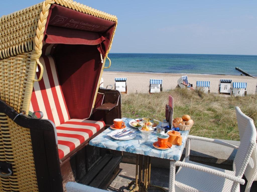 奥斯赛拜-屈隆斯博恩Fewo Schwalbennest am Meer-exklusiv-eigener Strandzugang的海滩上一张桌子、椅子和餐桌