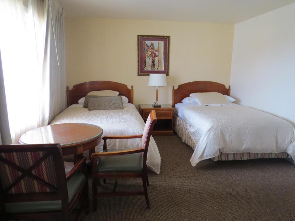 滨海城拉古那山林小屋的酒店客房,设有两张床和一张桌子及椅子