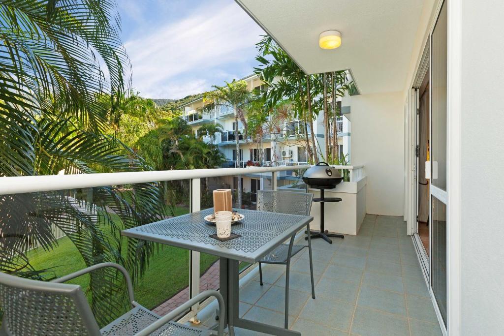 棕榈湾热带天堂度假酒店的阳台配有桌椅和棕榈树。