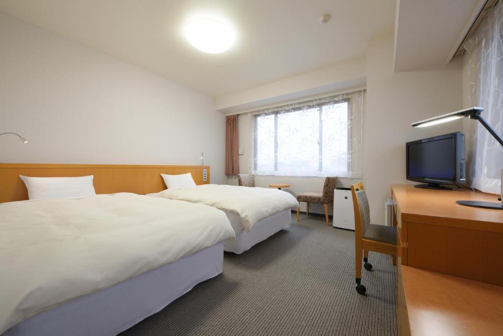大馆市大馆市格兰德公园酒店的酒店客房设有两张床、一张桌子和一台电视。