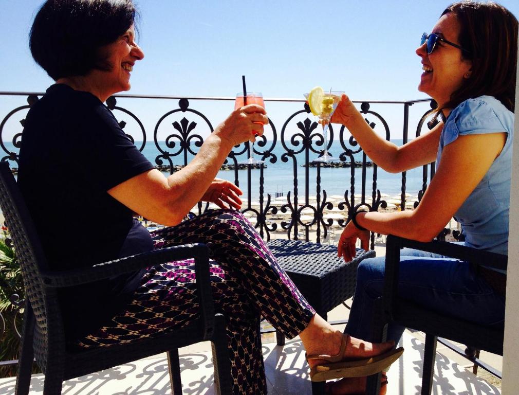 滨海库普拉Hotel Baia Marina的两人坐在阳台上喝饮料