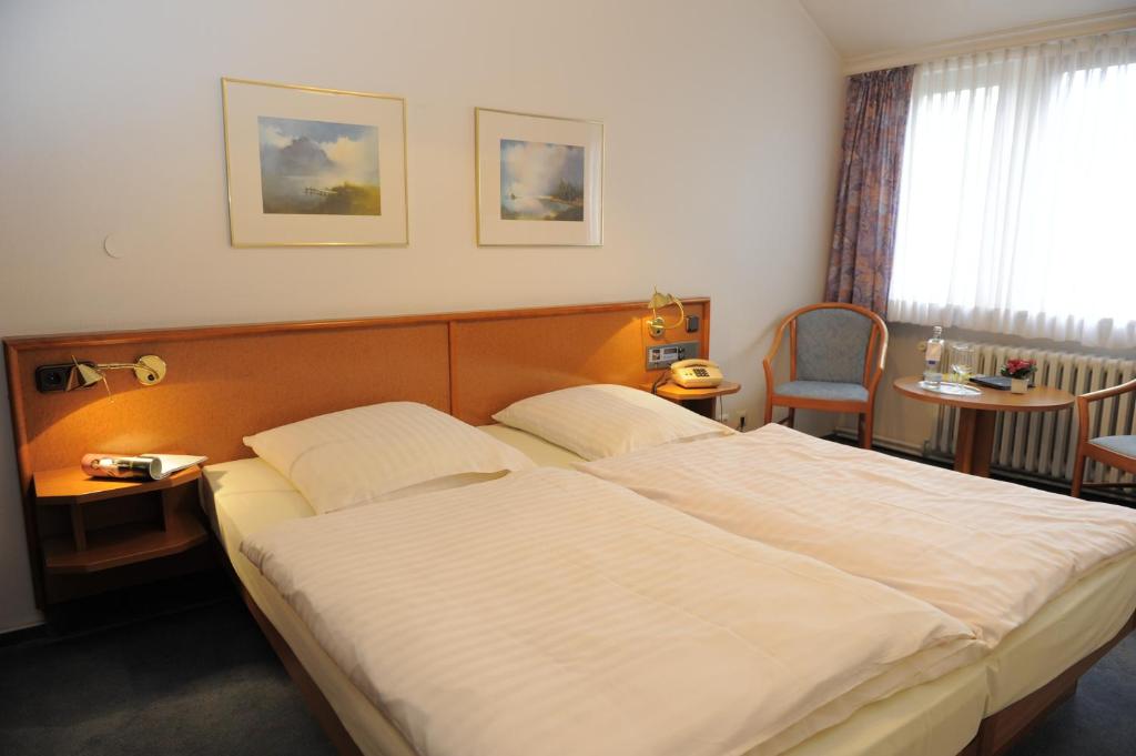 不莱梅黑尔特酒店的卧室配有一张白色大床和一把椅子