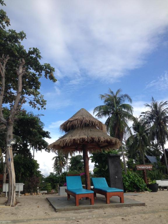 通萨拉Tropicana Khophagan Resort Hotel的海滩上一把稻草伞下的两把蓝色椅子