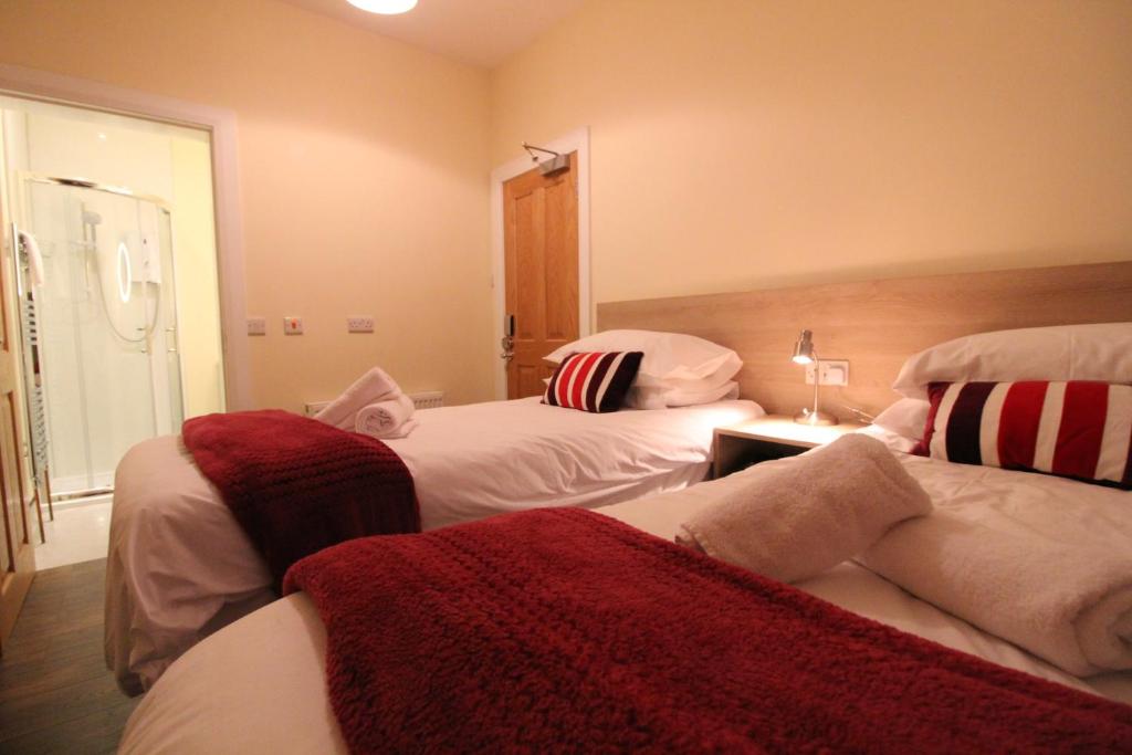贝尔法斯特Townlets Townhouse的一间卧室配有两张带红白毯子的床