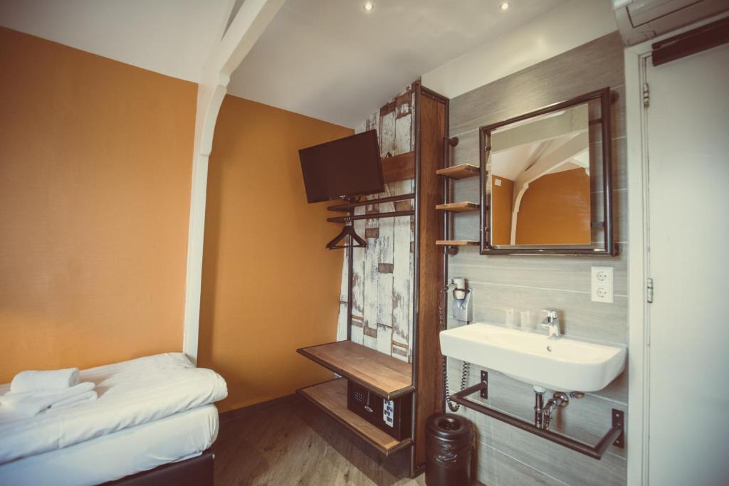 阿姆斯特丹经济型旅游酒店的一间带水槽和镜子的浴室以及一张床