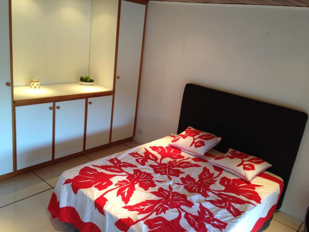 帕皮提Wendy Location的一间卧室配有一张带红白毯子的床